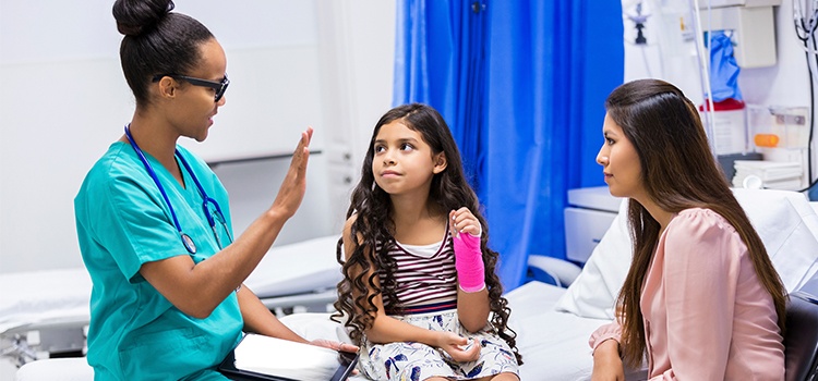 minority nurse talking to mom and child in exam room