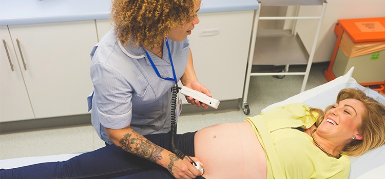 nurse midwife examines expectant mother with a measuring device