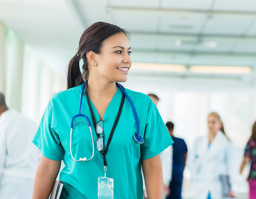 nurse walking through hospital hallway wearing stethoscope 