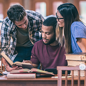 three students study in college library
