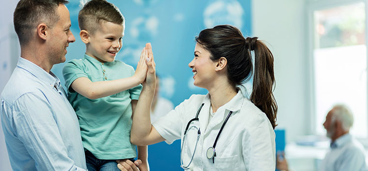 nurse practitioner high fiving smiling young patient with parent