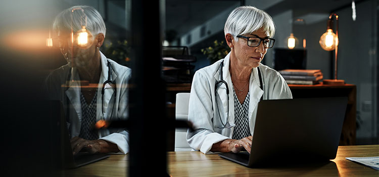 woman works on laptop in dimly lit office
