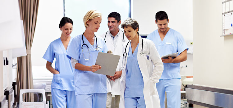 medical professionals looking at chart in hospital hallway