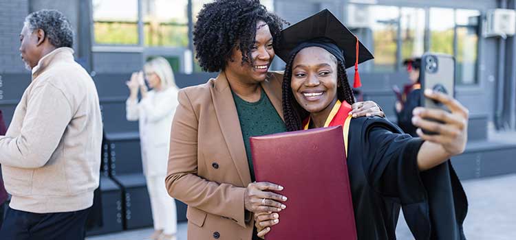 daughter taking selfie with mother at graduation