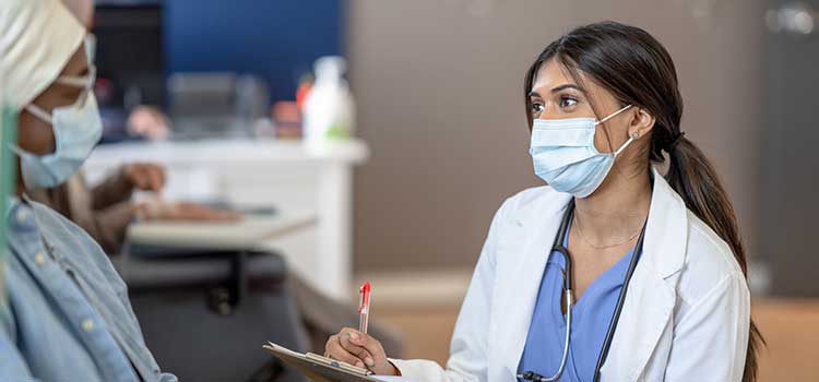 nurse speaking with patient in scarf