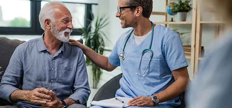 nurse comforting older man in chair