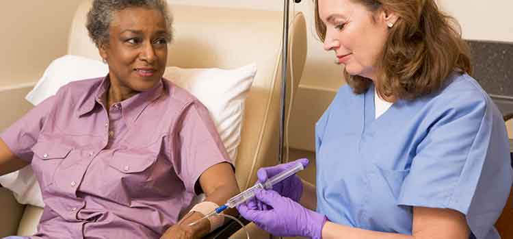 nurse administering chemo via IV to older patient