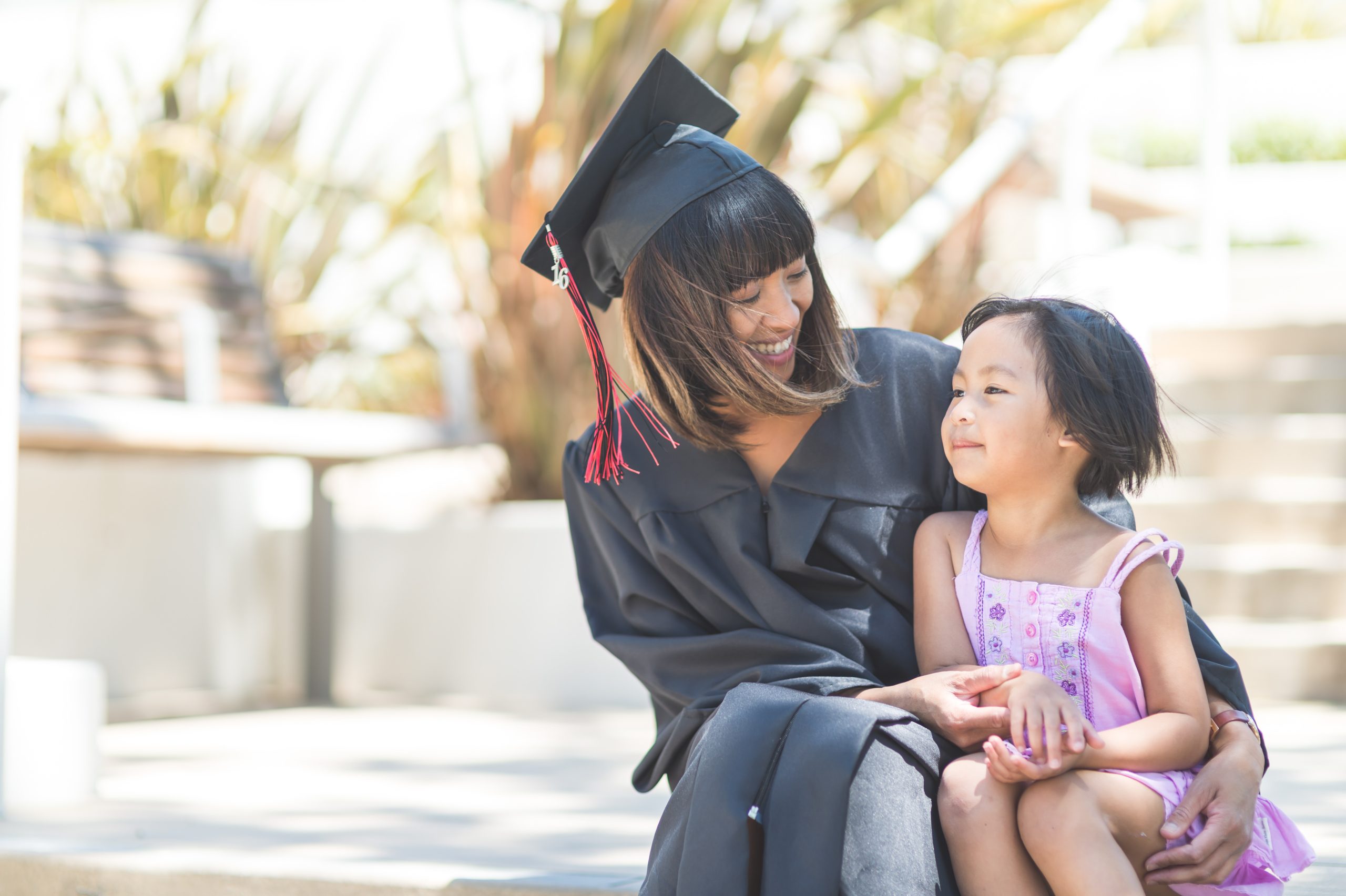 female graduate sitting on steps with young daughter