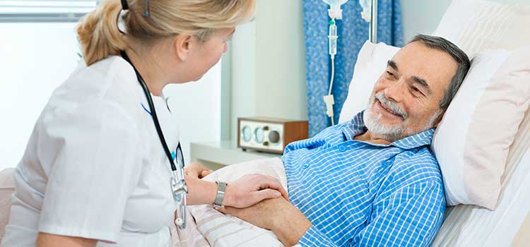 nurse comforting man in hospital bed