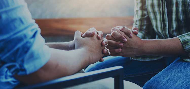 chose up of hands of two men praying together