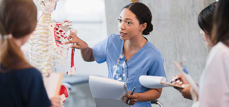 nursing instructor showing students instructional skeleton