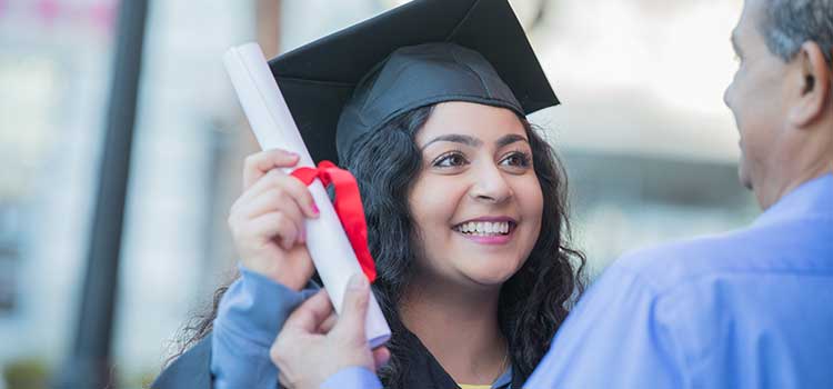 woman in cap and gown receiving diploma