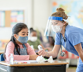school nurse checking temperature of young student at desk
