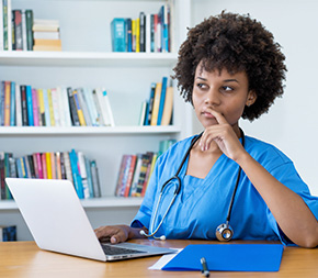 nurse with laptop computer looking contemplatively in office