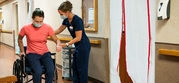 nurse assists injured patient into wheelchair