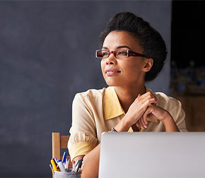 woman sitting at laptop computer looking away contemplatively