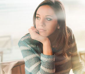 young woman working on laptop computer looking away contemplatively