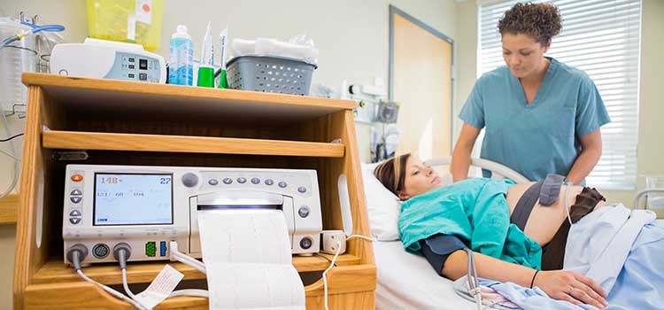 labor nurse monitors pregnant patient