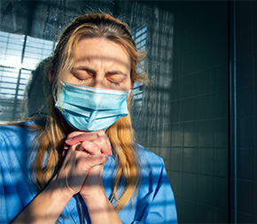 woman nurse with mask praying