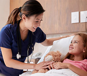 smiling nurse with child patient in hospital room