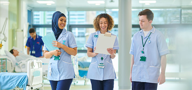 three nurses walking and talking in medical facility