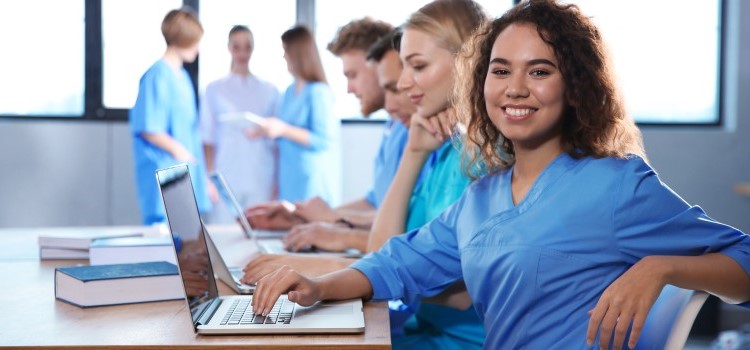 nurse smiling while working on laptop