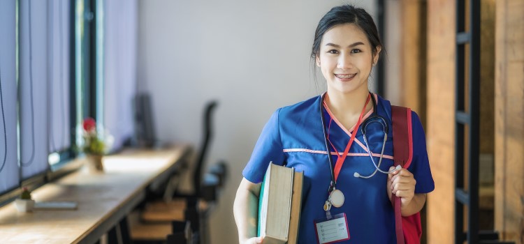 nursing student posing with stethoscope and text books
