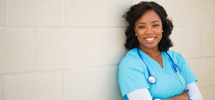 Female nurse standing by wall with arms crossed