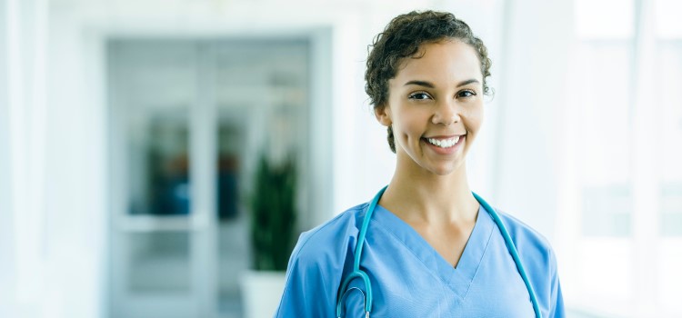 Female nurse poses in front of a hallway