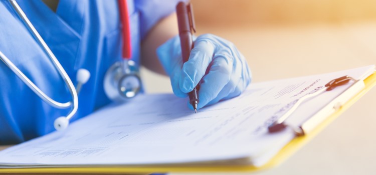 Nurse writing on clipboard with pen