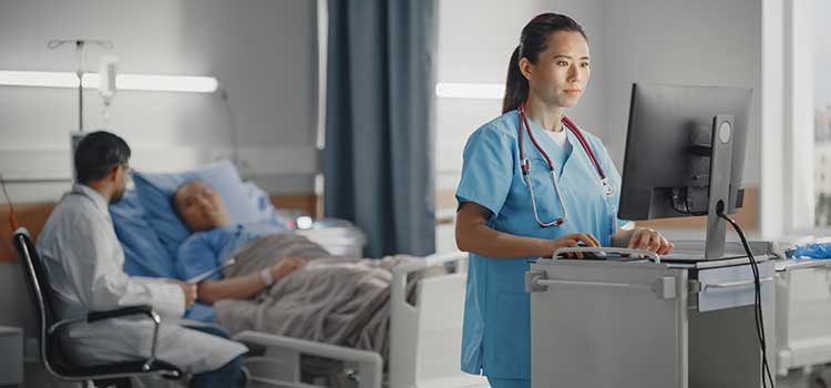 nurse adds patient vitals to chart in room