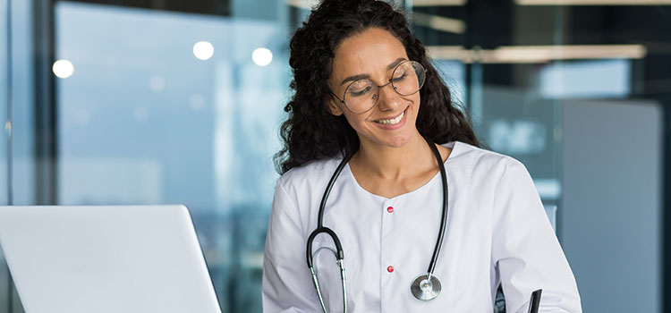 nurse studies on laptop and takes notes