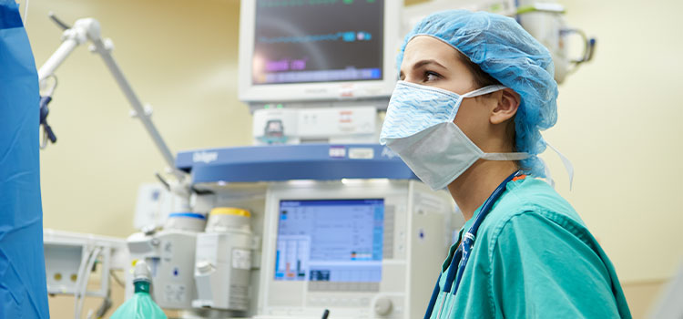 nurse in mask monitors patient vitals