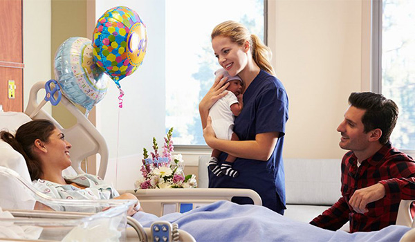 labor and delivery nurse hold newborn and talks to mother