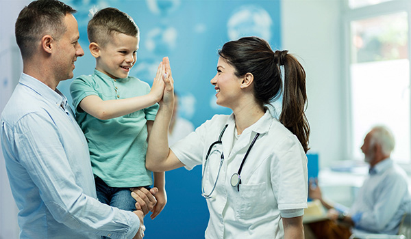 nurse high five child patient held by father