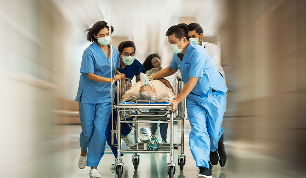 team of nurses run down corridor with injured patient on gurney
