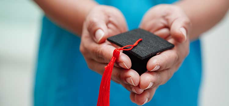 nurse graduate holds mortarboard in hands