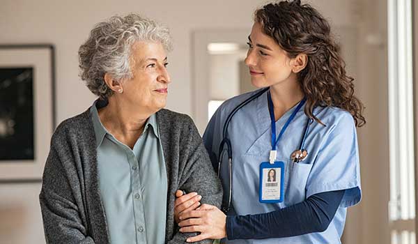 geriatric nurse strolls with smiling elderly patient