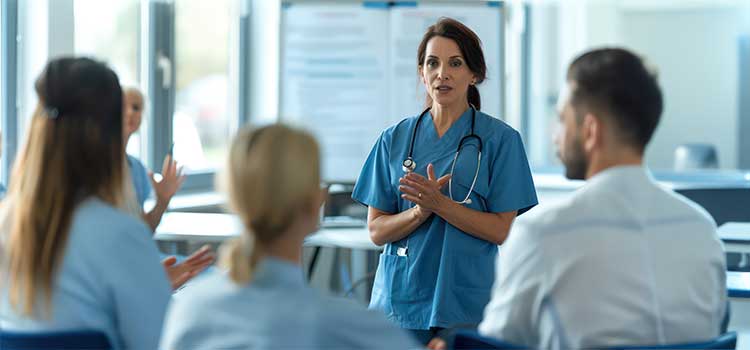 bsn nurse leads team meeting before nurses go on shift
