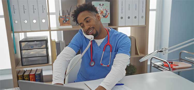 male nurse reviews patient status on phone at hospital nursing station