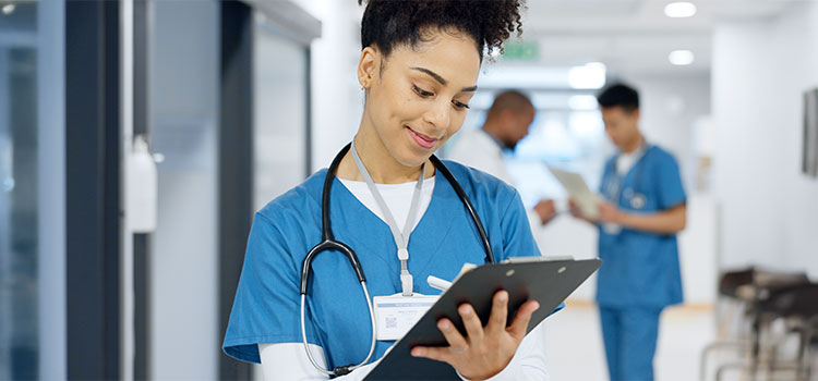 nurse makes notes in patient chart while doing her rounds in hospital