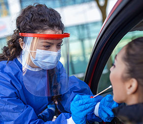 a public health nurse administers a covid test swab at a drive-through testing center