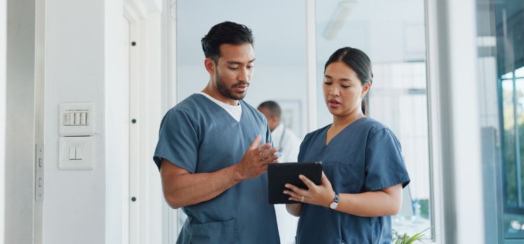 two nurses discuss a patient's chart on an electronic tablet