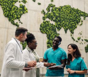 global nurses and doctors converse in front of a mural of the world